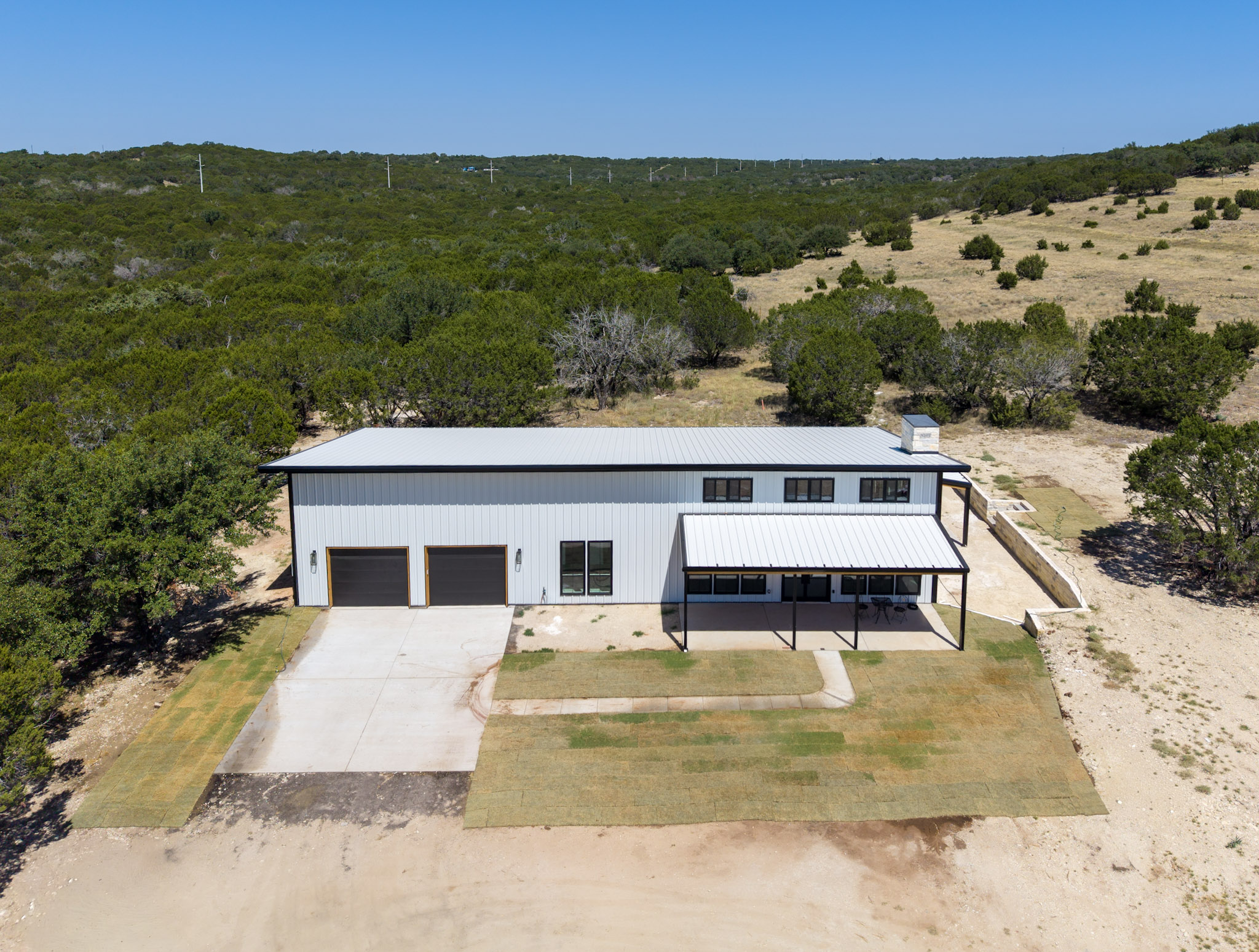 Barndominium and attached shop seen from the air on hill country acreage