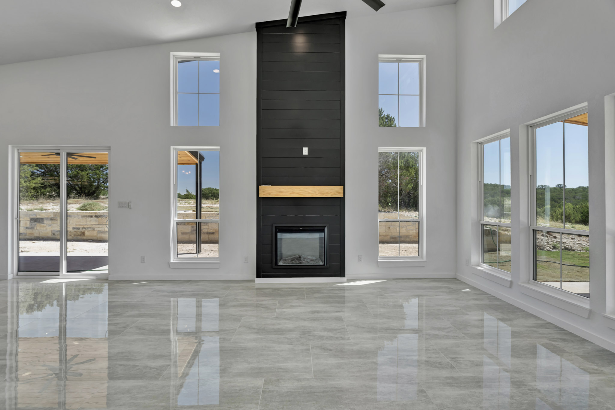 Great room with a floor to ceiling black shiplap fireplace and cedar mantel