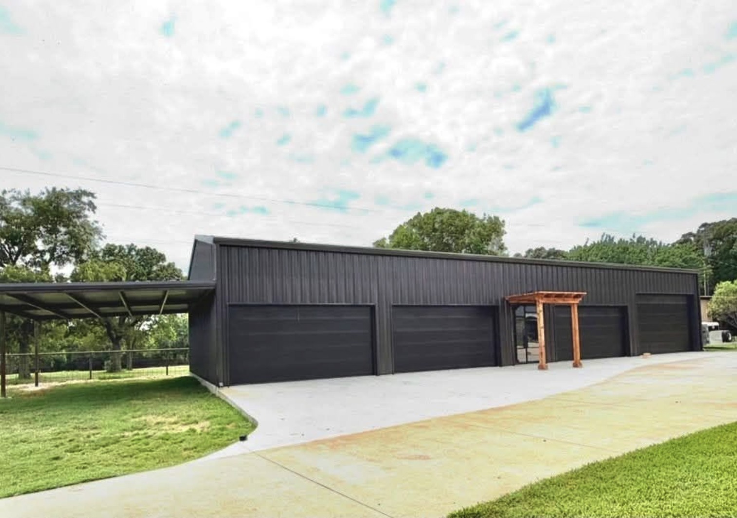 Black four bay shop with a concrete apron and a timber entry