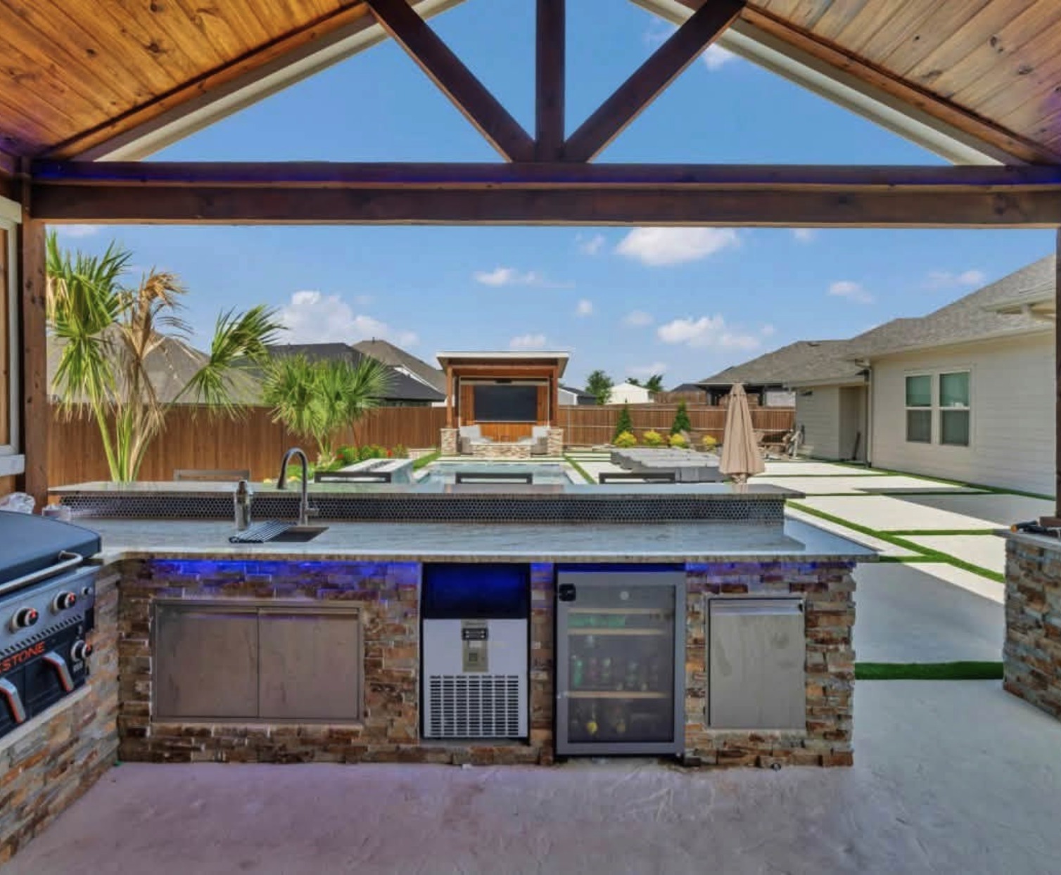 Poolside stone kitchen with a sink, refrigeration and counter seating