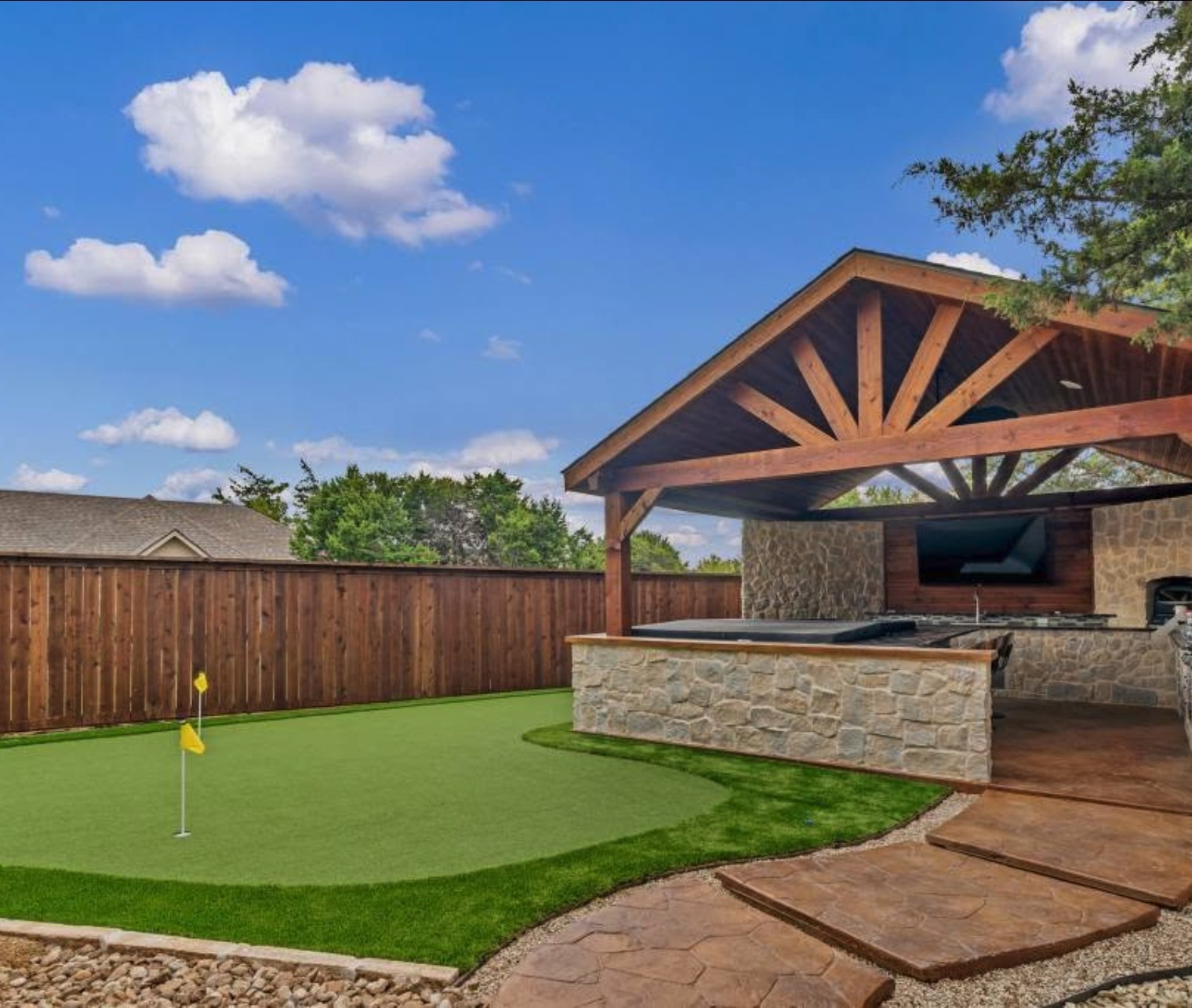 Cedar gable pavilion and stone kitchen beside a putting green