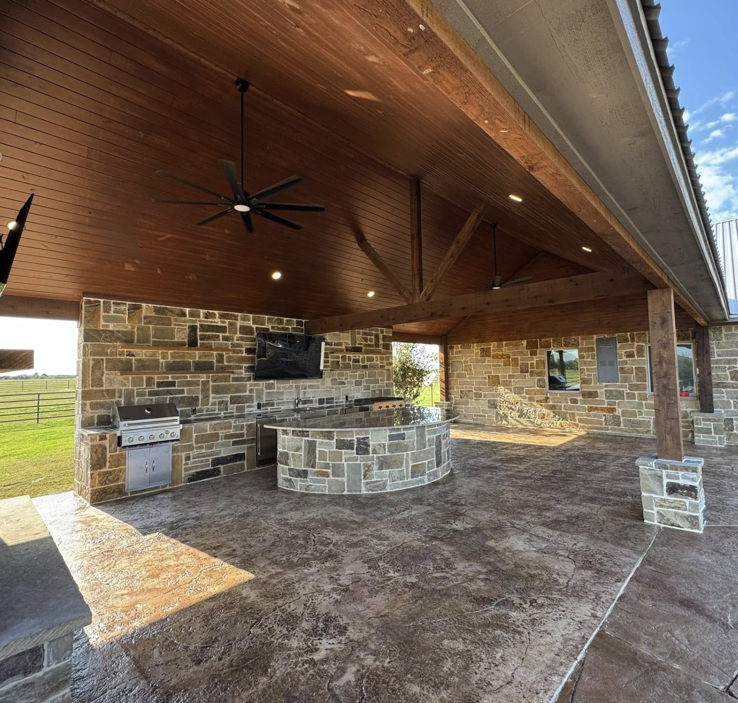 Curved stone outdoor kitchen island with granite top