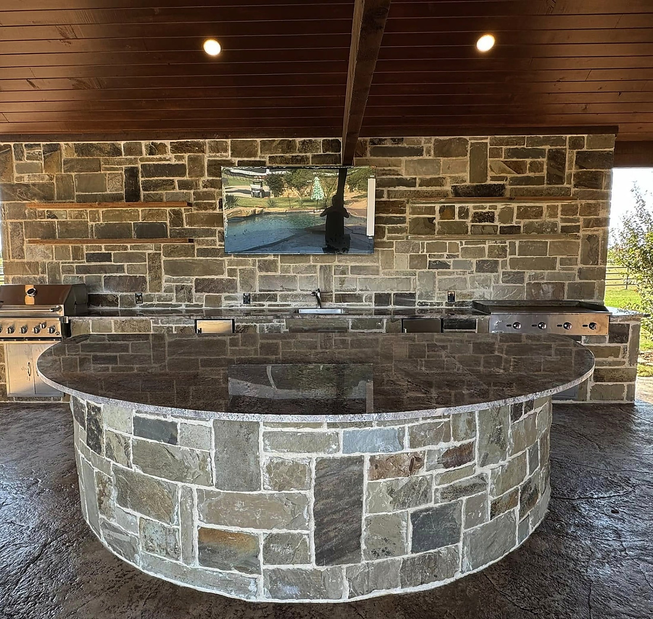 Curved stone bar with a mounted TV and a full cooking run