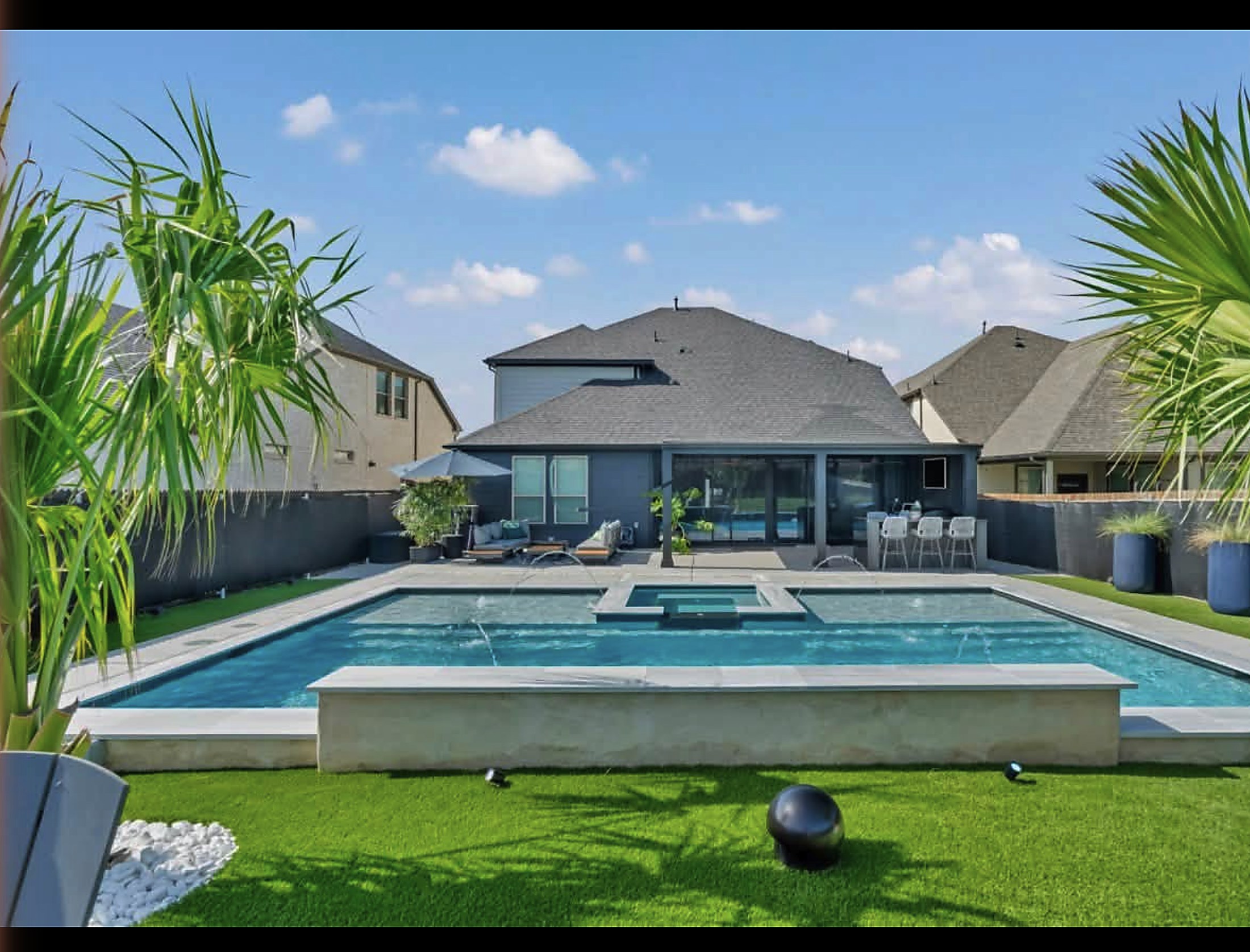 Pool and raised spa with turf surround and a covered patio behind