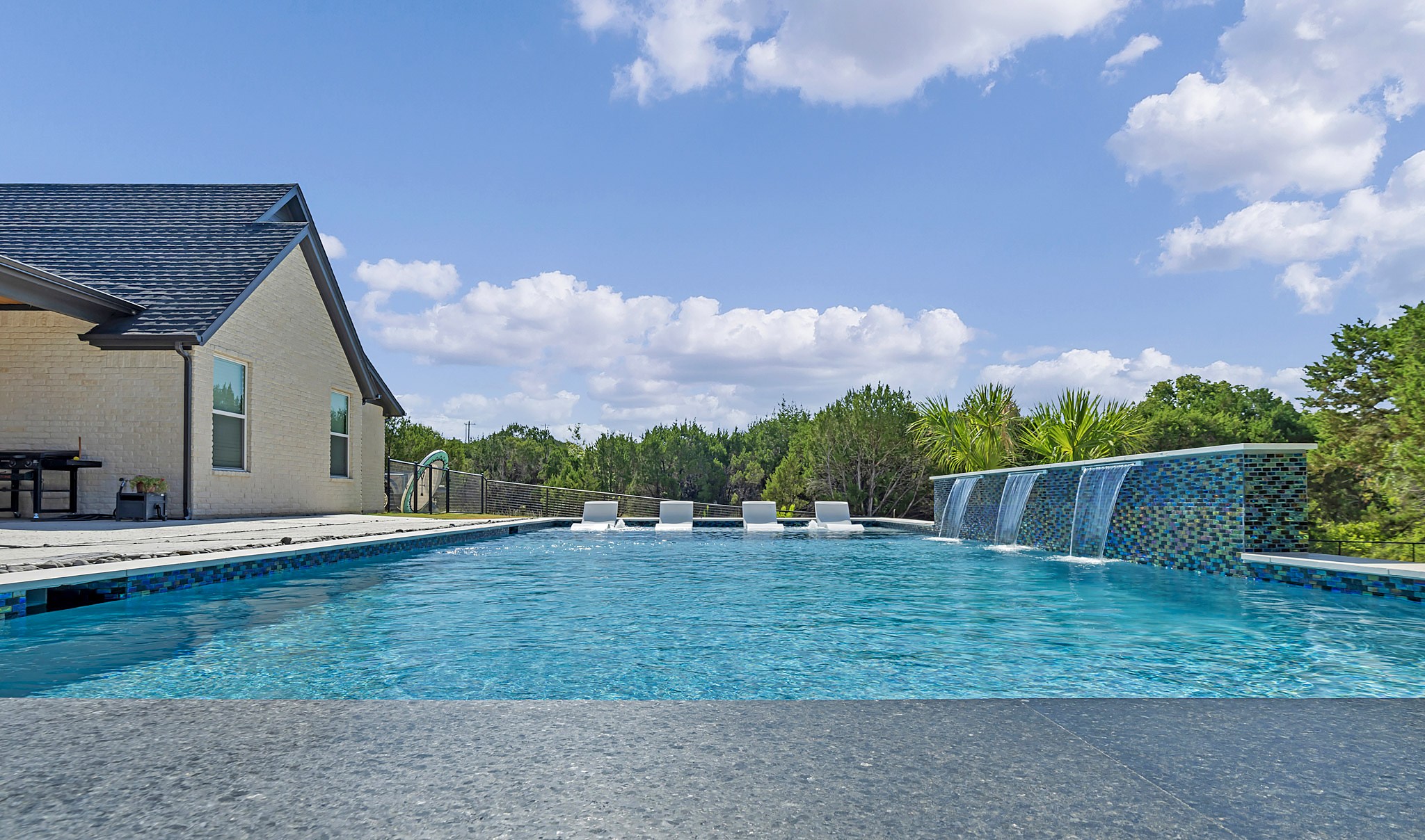 Finished gunite pool with a tiled sheer descent wall and open treeline behind