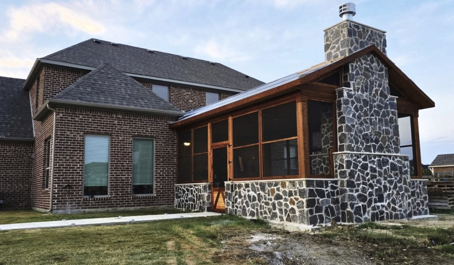 Screened porch addition with stone fireplace on an existing brick home