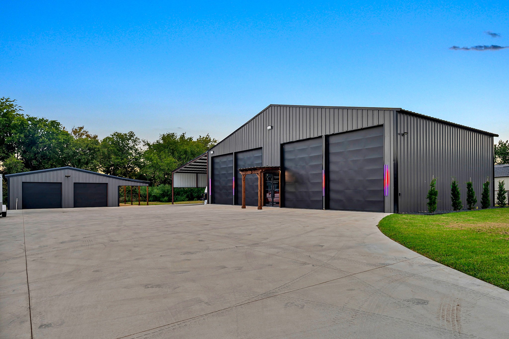 Grey metal shop with four roll up doors and accent lighting